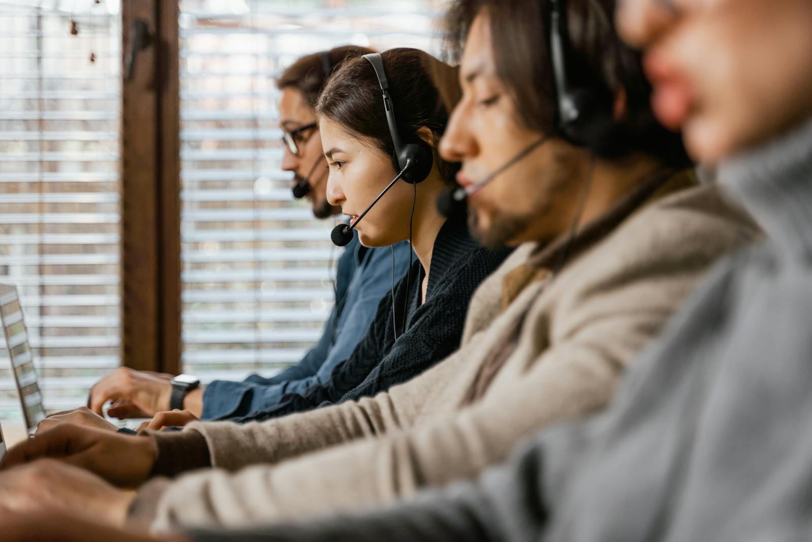 Customer operations team using laptops and headsets in a call centre.