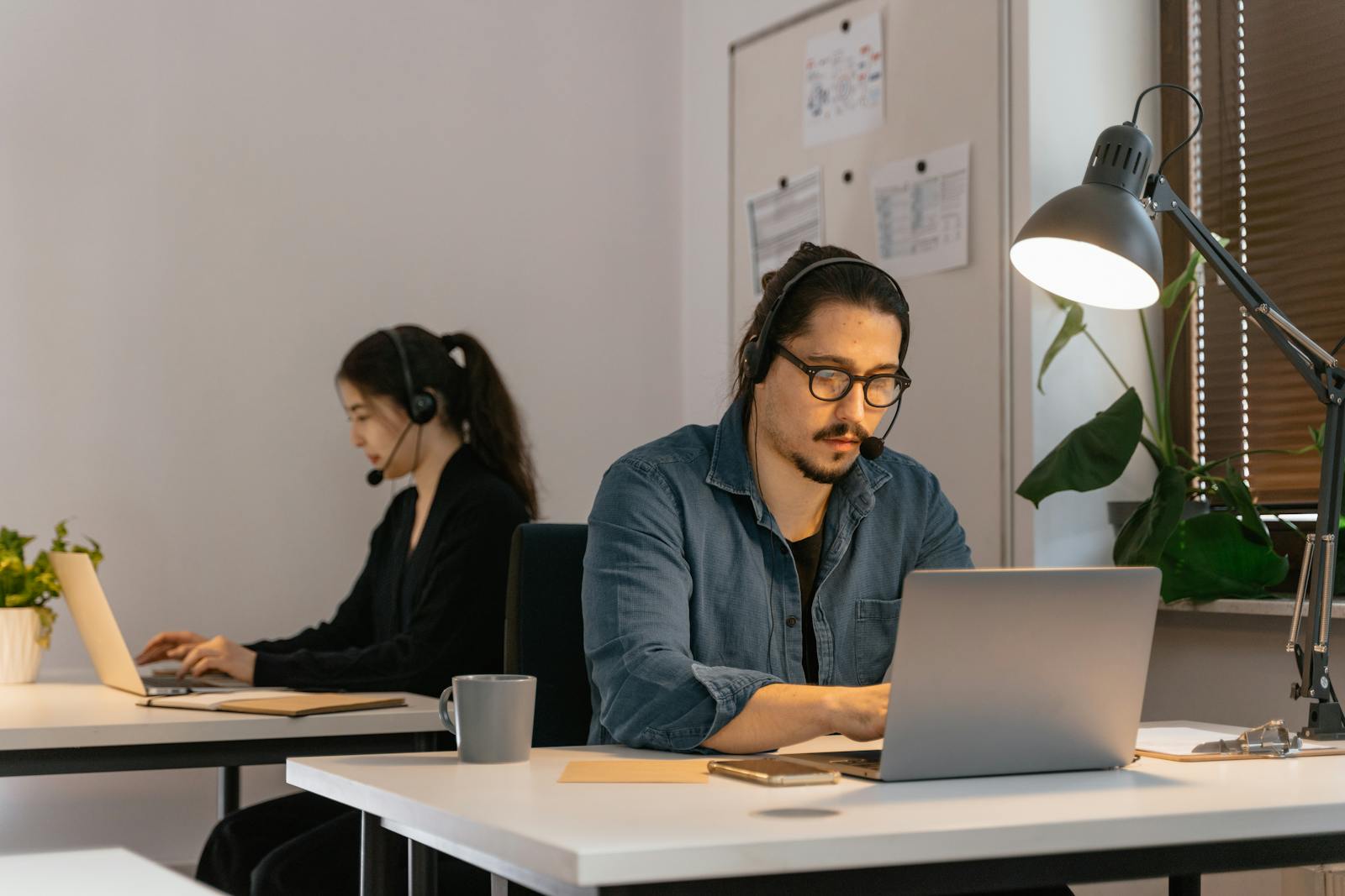 Customer support team using laptops and headsets in a modern office.